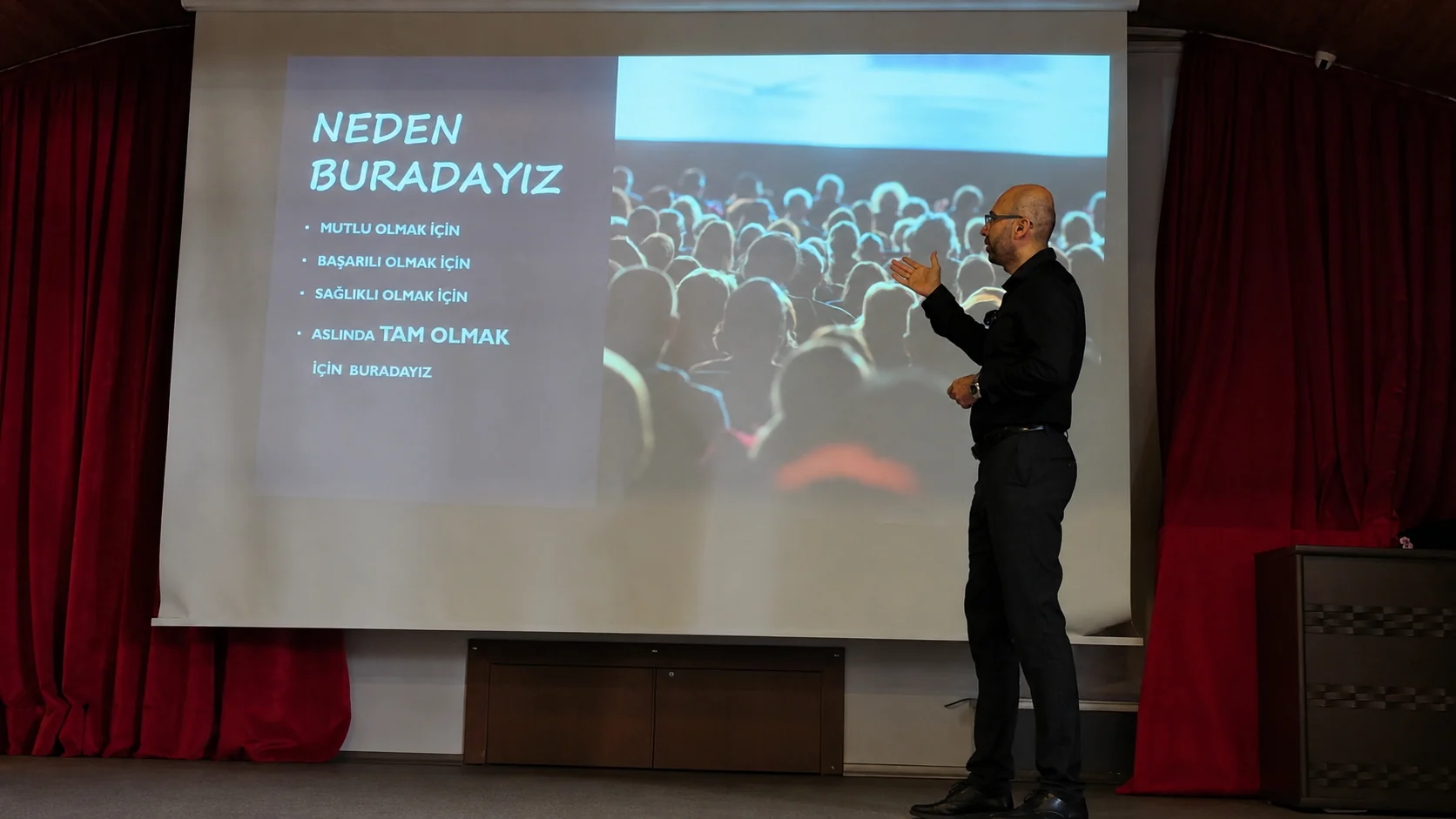 Mehmet Akif Kuşaslan sahnede eğitim verirken; perdede “Neden buradayız” slaydı