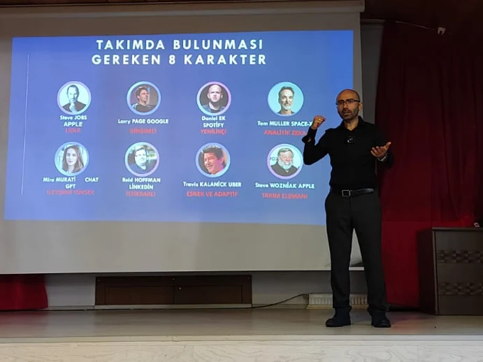 Mehmet Akif Kuşaslan sahnede eğitim verirken; perdede “Takımda bulunması gereken 8 karakter” slaydı